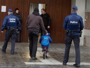 A man wheels a boy on his bicycle past police officers as they arrive for school in the center of Brussels on Wednesday, Nov. 25, 2015. Students in Brussels have begun returning to class after a two-day shutdown over fears that a series of simultaneous attacks could be launched around the Belgian capital. (AP Photo/Virginia Mayo)