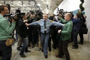 Media scuffle with UN security officer as French foreign affairs minister Laurent Fabius walks out of the COP21 conference in Le Bourget, Saturday, Dec.12, 2015. French foreign minister Laurent Fabius says a "final" draft of a global climate pact would be legally binding. (AP Photo/Laurent Cipriani)
