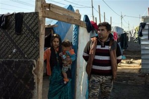 In this Monday, Dec. 7, 2015, photo, Abdul Khader Eido, a Sunni Muslim from Sinjar, stands with his wife and son in Harsham camp, where he lives with his family after fleeing Islamic State militants over a year ago. Islamic State militants who stormed into the Iraqi town of Sinjar in 2014, massacring members of the Yazidi minority and forcing women into sexual slavery, are gone. But Sunni Muslims who lived alongside the Yazidis there for generations say their own nightmare is far from over and many have yet to return, saying they fear revenge attacks. (AP Photo/Alice Martins)