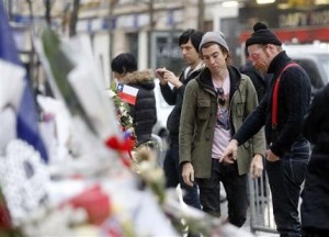 Members of the band Eagles of Death Metal, Jesse Hughes, right, and Julian Dorio pay their respects to 89 victims who died in a Nov. 13 attack at the Bataclan concert hall in Paris, France, Tuesday, Dec. 8, 2015. Members of the California rock band Eagles of Death Metal are back at the ravaged Paris theater where they survived a massacre by Islamic extremist suicide bombers. (AP Photo/Jacques Brinon)