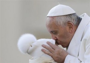 Pope Francis kisses a child upon his arrival for the weekly general audience at the Vatican, Wednesday, Dec. 16, 2015. Pope Francis enters his 80th year on Thursday amid mounting hopes among his critics that it will be his last _ at least as pope. (AP Photo/Gregorio Borgia)