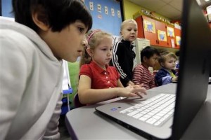 In this photo taken Nov. 4, 2015, kindergartner Lauren Meek, second left, works with a pair of second graders as they work on programming during their weekly computer science lesson at Marshall Elementary School in Marysville, Wash. The school, north of Seattle, joined a growing movement nationwide to expose more public school children to computer science, even as early as in kindergarten. Backed by technology leaders, nonprofits and companies, schools in New York, San Francisco and other cities have committed to offer computer science to students in all grade levels. (AP Photo/Elaine Thompson)